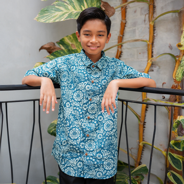 a boy in a lifestyle photo posing in a batik shirt in the pattern teal ukir