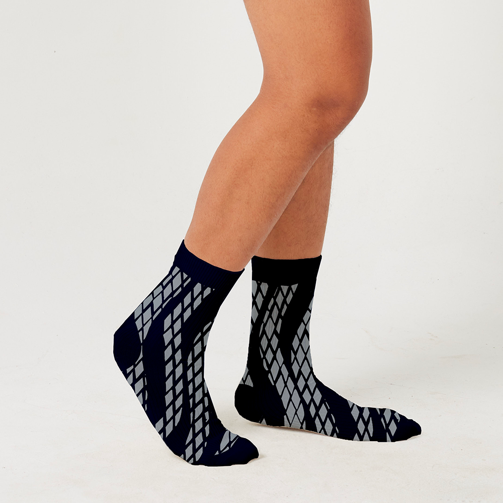 a model wearing a new pattern black snakeskin socks against a white background