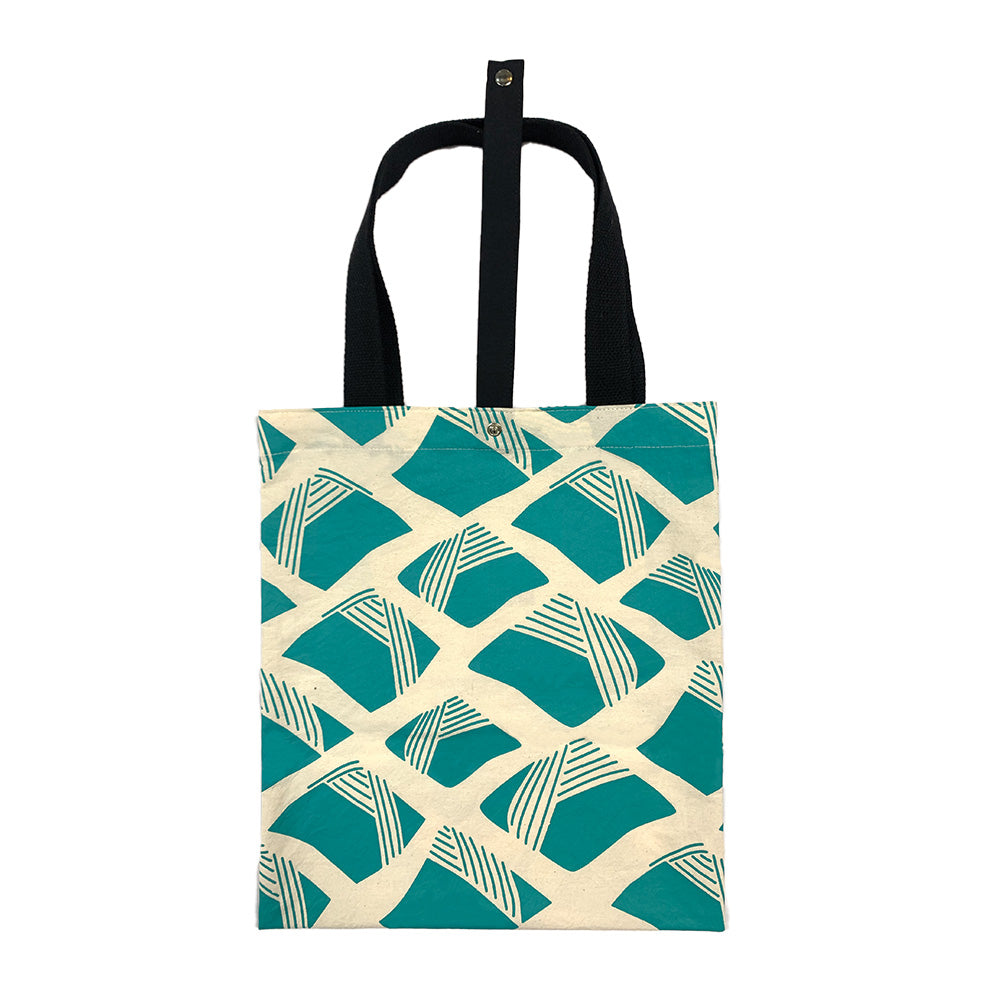A batik totebag or even a shopping bag with pattern inspired from Nasi Lemak in turquiose color and put on a white background. This photo show the front side of the bag