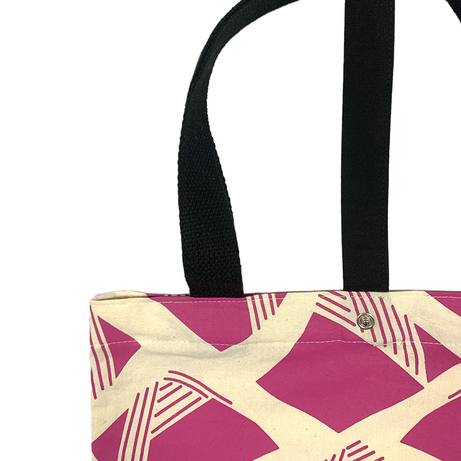 A batik totebag or even a shopping bag with pattern inspired from Nasi Lemak in fuchsia color and put on a white background. This show the closeup photo of the bag