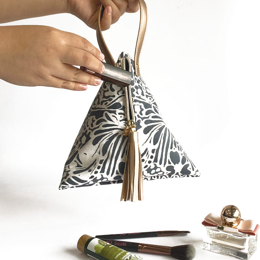 a lifestyle photo of the ketupat bag made of batik in the pattern grey peony against a neutral background