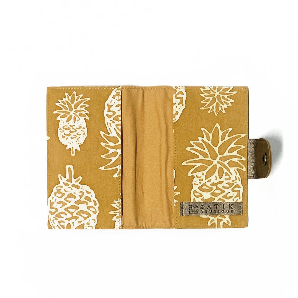 a photo of a passport cover in the pattern golden pineapple showcasing the inside made of batik