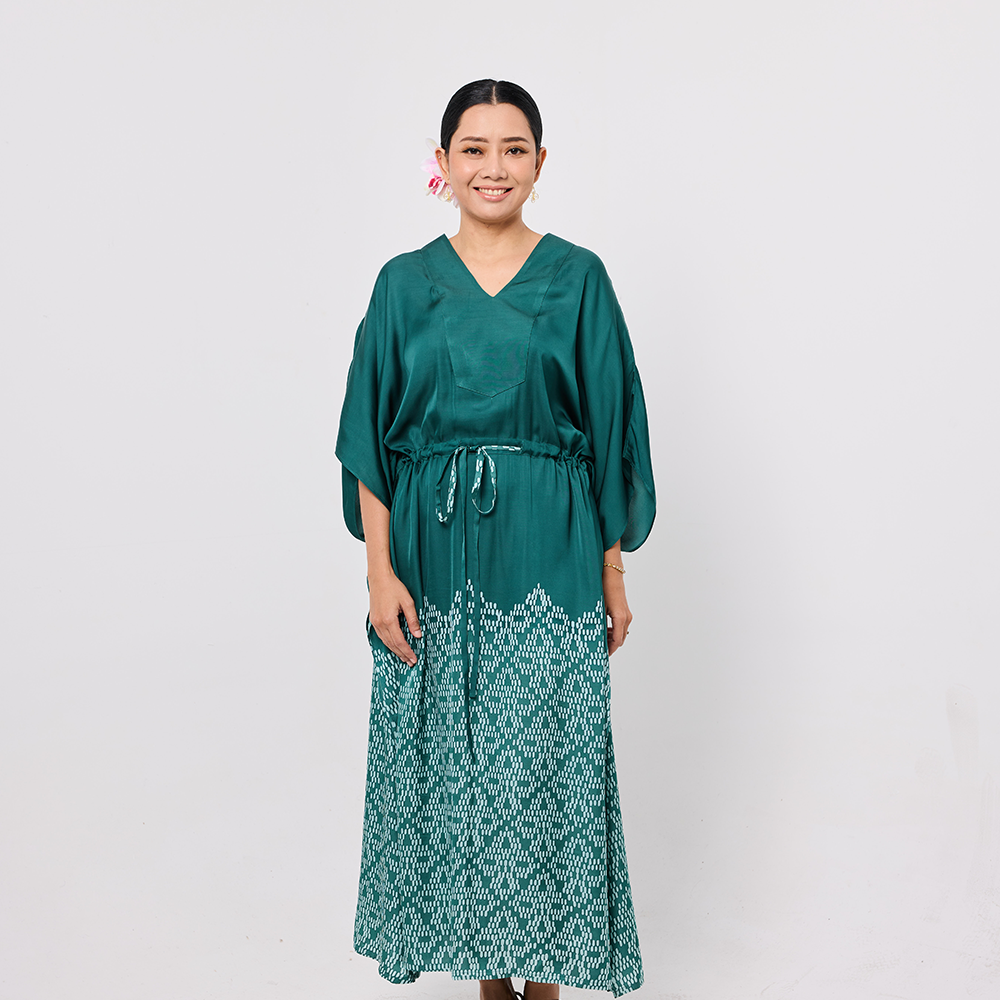 Woman wearing a green dress with a white pattern on a plain background