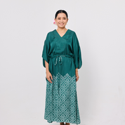 Woman wearing a green dress with a white pattern on a plain background