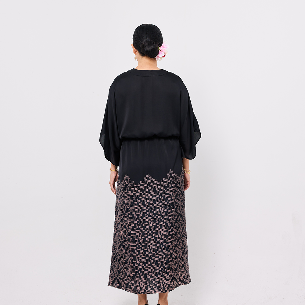 Woman wearing a black top and patterned skirt on a white background