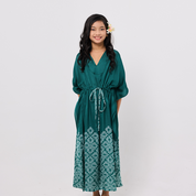 Girl wearing a green dress with a white pattern on a plain background