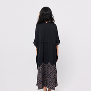 Woman wearing a black dress with a patterned hem on a white background