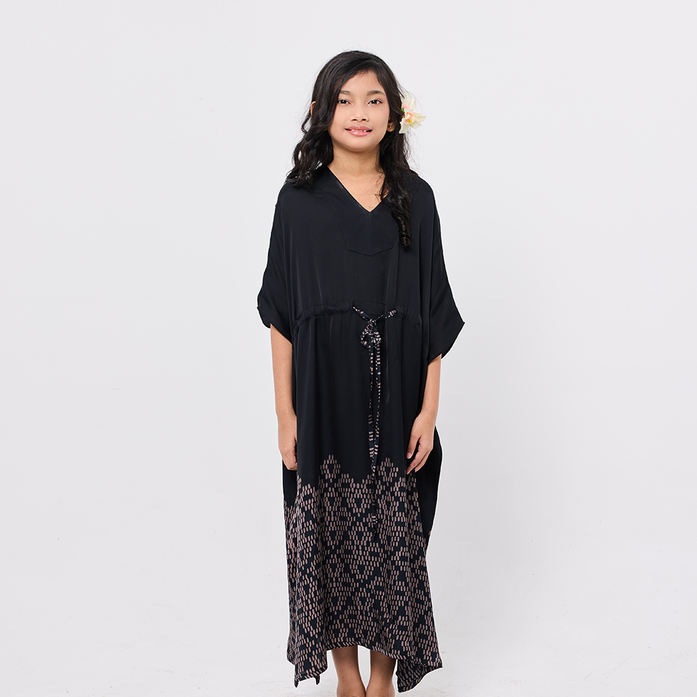 Woman wearing a black dress with a patterned hem on a white background