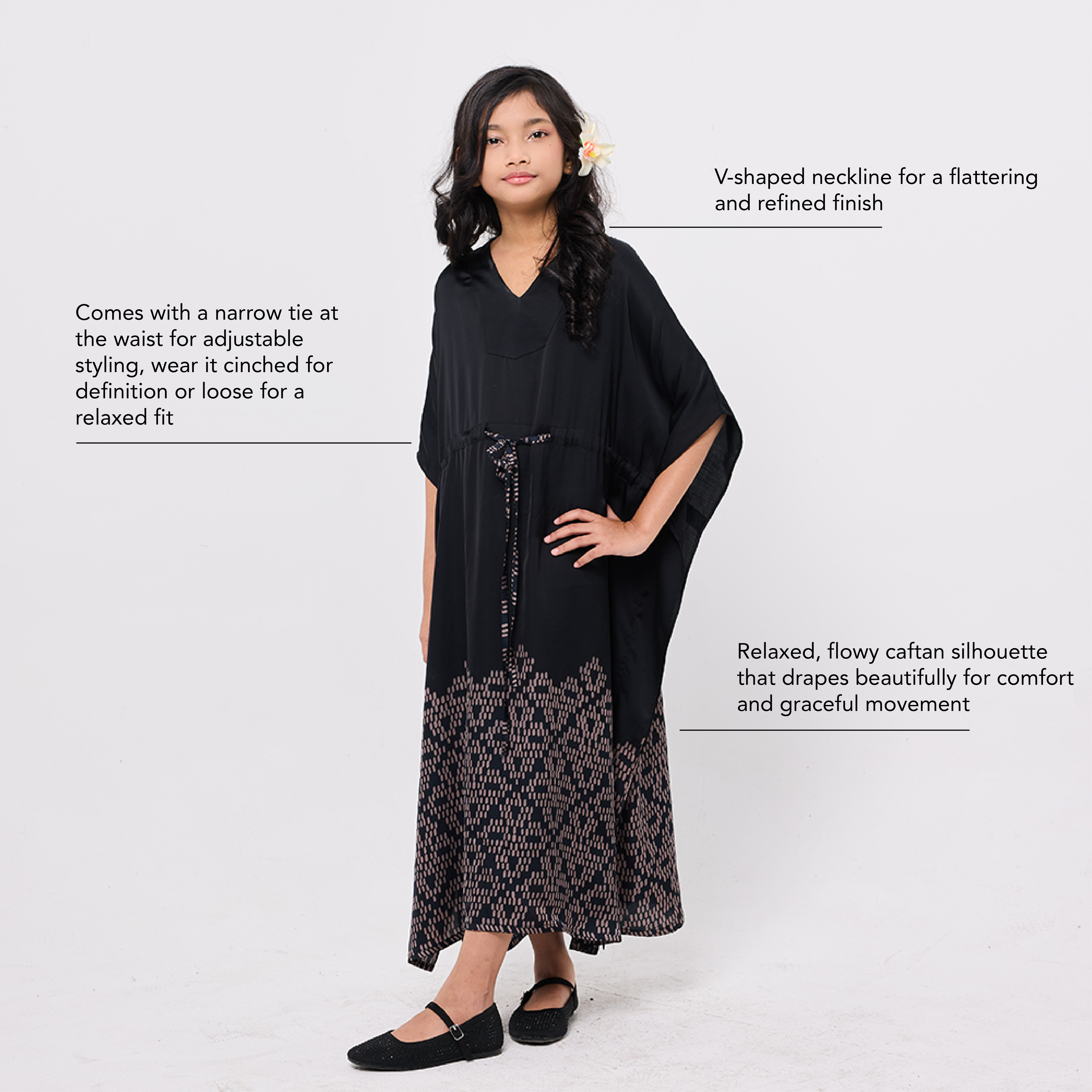 Woman wearing a black dress with a V-shaped neckline and floral details on a white background