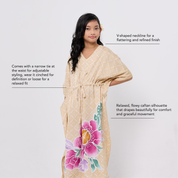 Woman wearing a beige caftan with floral designs on a white background