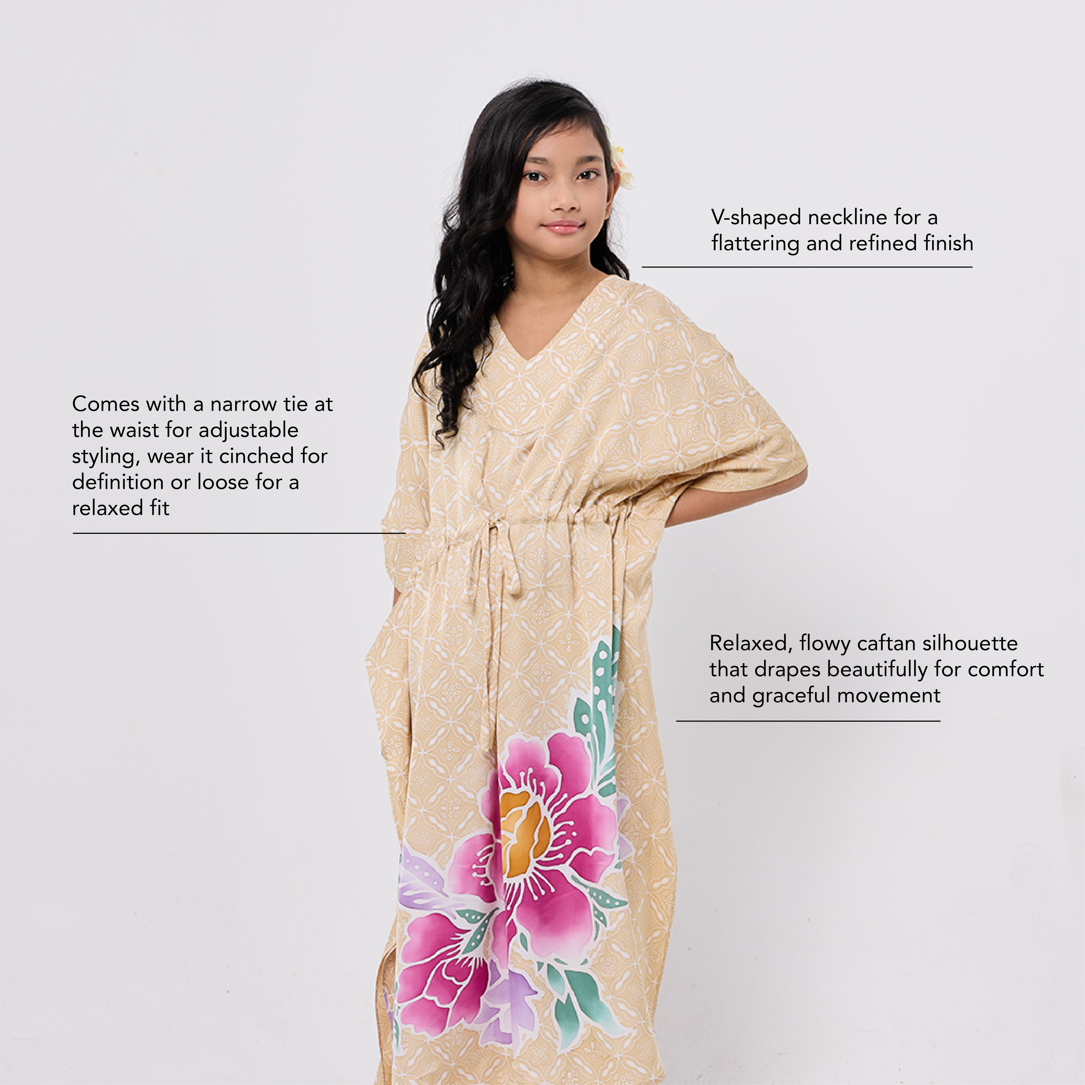 Woman wearing a beige caftan with floral designs on a white background