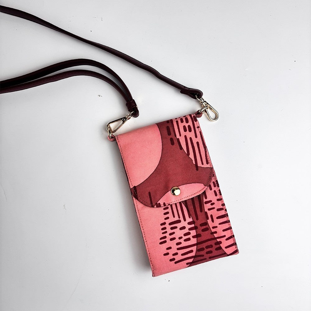 Pink crossbody bag with black abstract pattern on a white background