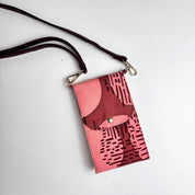 Pink crossbody bag with black abstract pattern on a white background