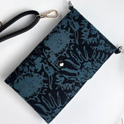 Black clutch bag with blue floral pattern on a white background