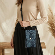 Person holding a blue patterned bag with a beige background