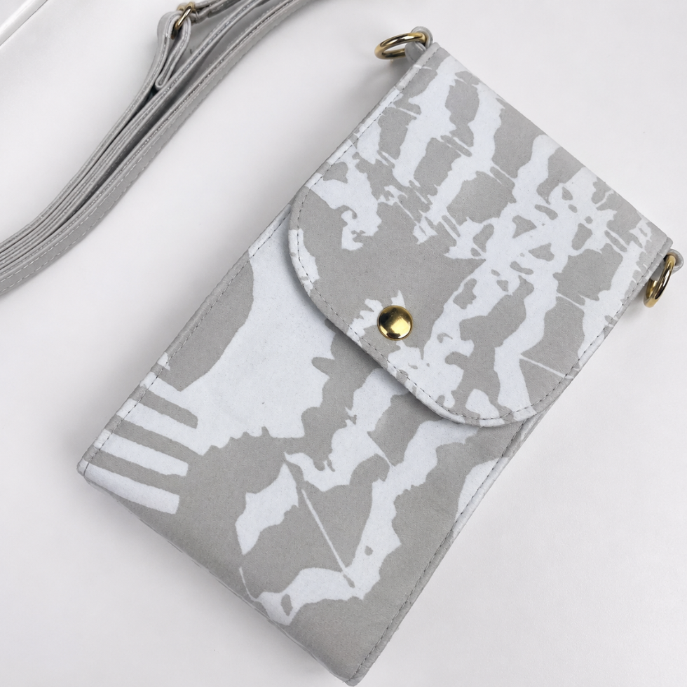 A gray and white abstract patterned crossbody phone bag with a gold snap button and gold-tone hardware, shown on a clean white background.