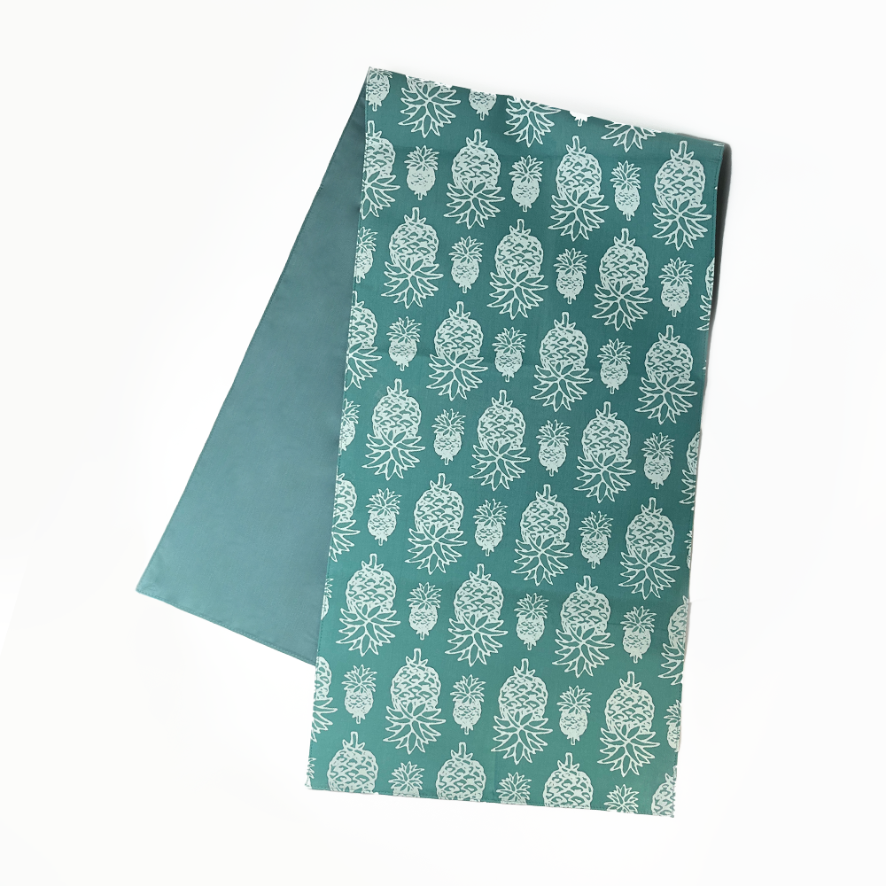 a white box photo of the table runner against a white background in the pattern turquoise pineapple