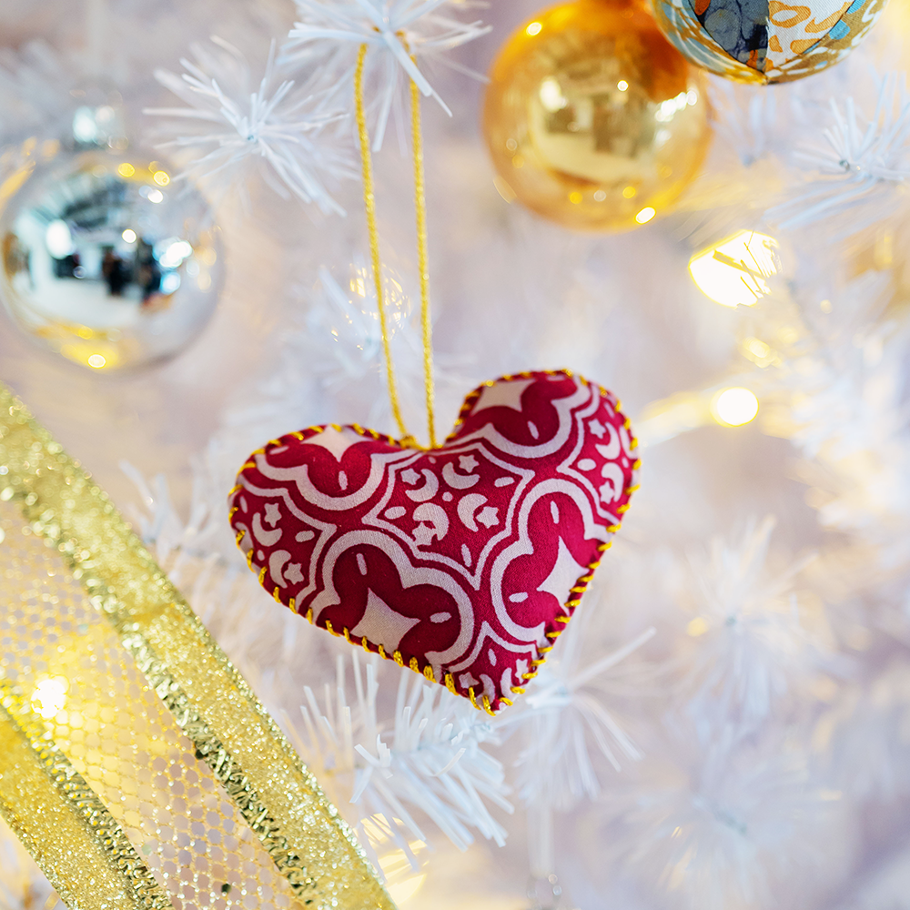 A lifestyle photo of batik handmadeheart shaped crimson celestial with golden string to hang on christmas tree