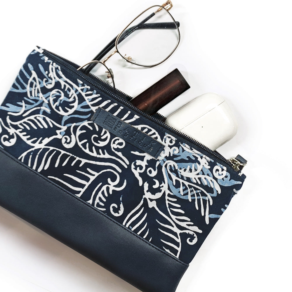 a photo of a zip pouch made of batik in the pattern blue nautical fern with props in front of a neutral background