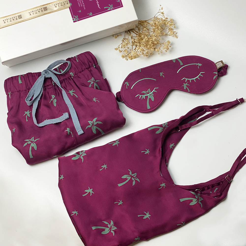 A lifestyle photo of batik loungewear set which consist of silk cotton camisole, shorts and eyemask in Fuchsia Palm