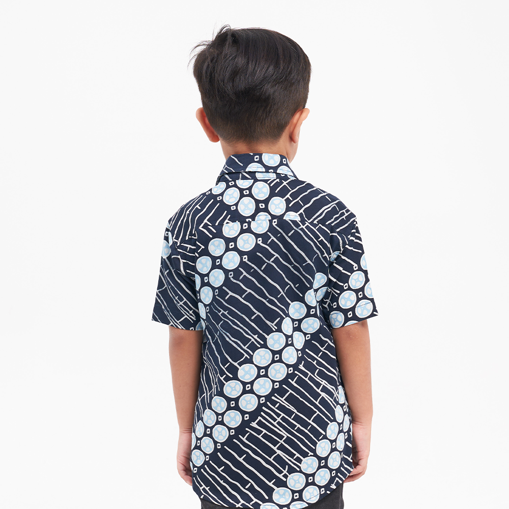 a boy wearing a batik shirt in the pattern navy buluh against a white background
