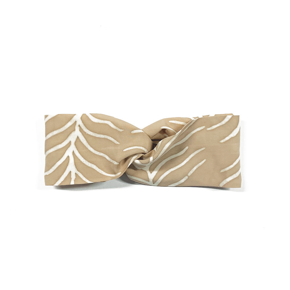 a whitebox flatlay of a latte fern headband made of batik against a neutral background