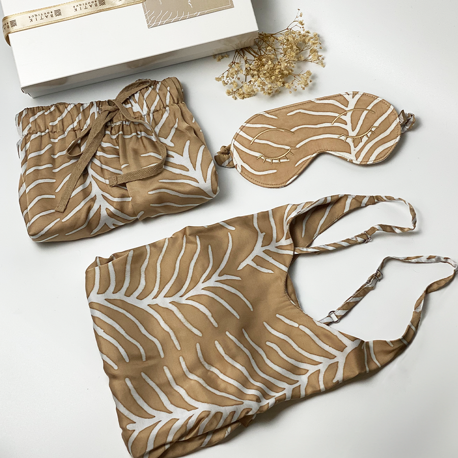 A lifestyle photo of batik loungewear set which consist of silk cotton camisole, shorts and eyemask in Latte Fern