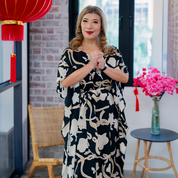 a woman posing in a CNY setting in a batik caftan dress 