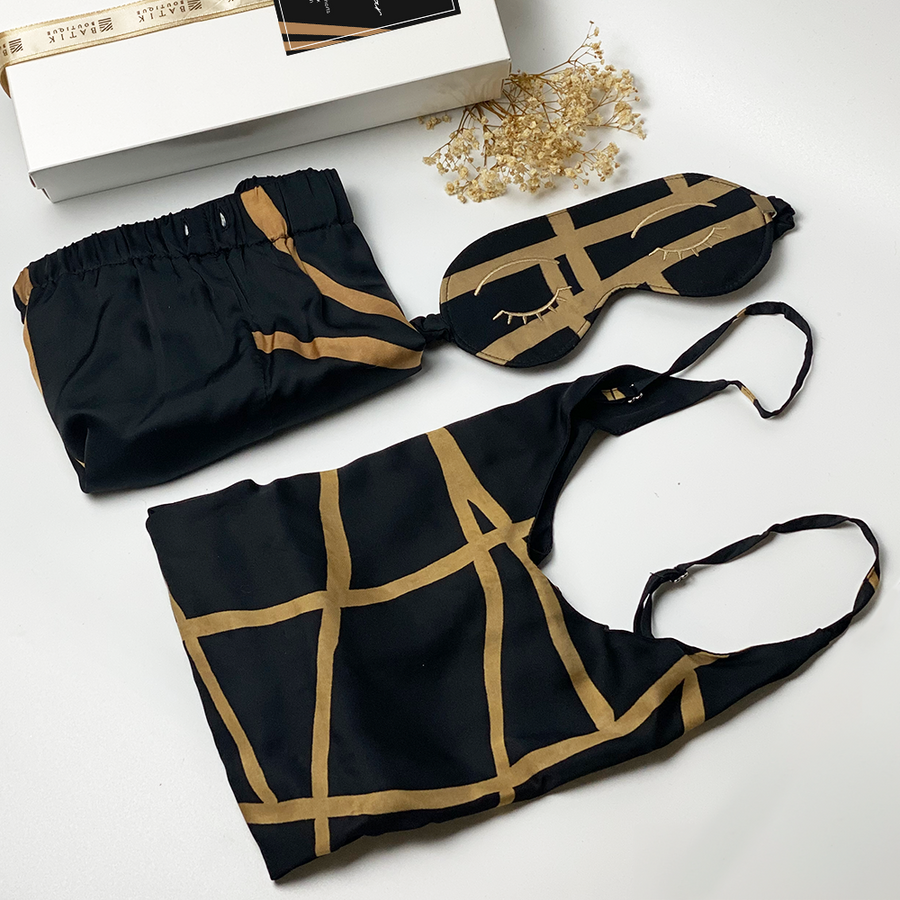A lifestyle photo of batik loungewear set which consist of silk cotton camisole, shorts and eyemask in Black Ecru