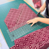 An seamstress is cutting batik fabric in crimson celestial pattern