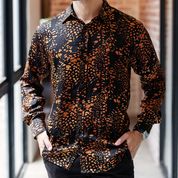 Close-up of Batik Boutique’s Black Leopard Batik Silk Shirt showing intricate hand-blocked motifs and fine silk texture in rich amber and black tones