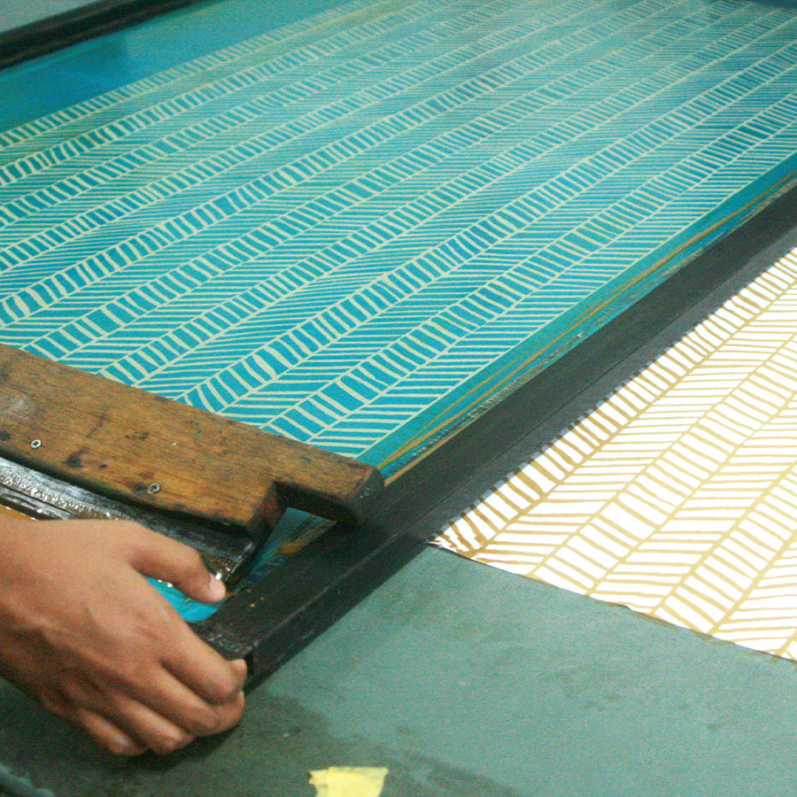 An artisan deeply engaged in the intricate process of making batik, employing the silkscreen technique with skill and precision