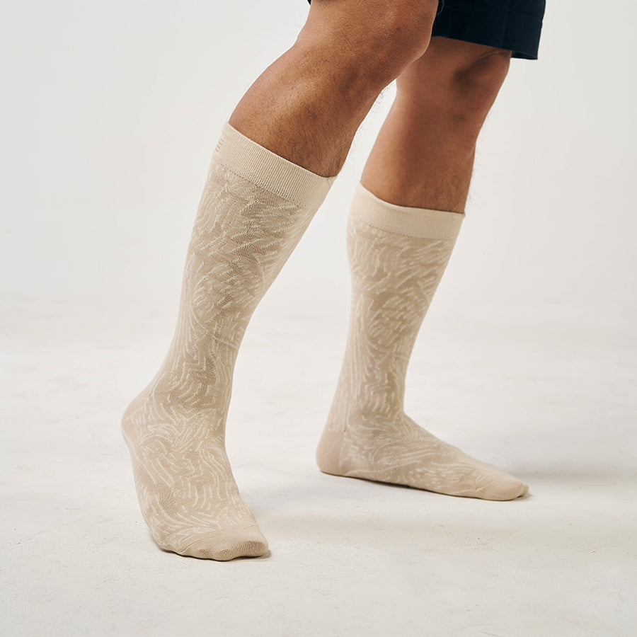 A model wearing batik-inspired socks in tan driftwood print