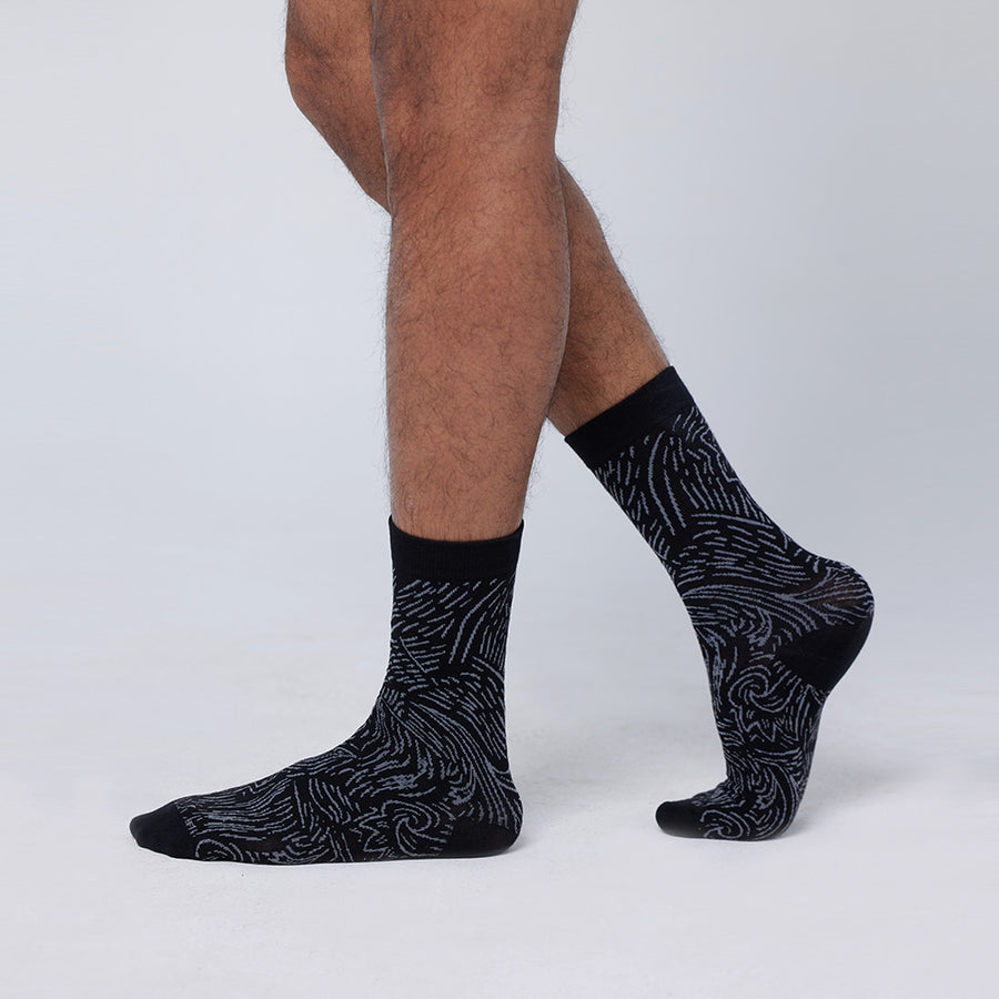 A model wearing batik-inspired socks in black driftwood print