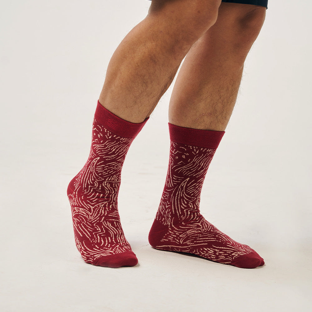 A model wearing batik-inspired socks in crimson driftwood print