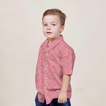 a boy posing in a rose bintang batik shirt against a neutral background