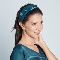 A model styling a batik headband in forest green pattern