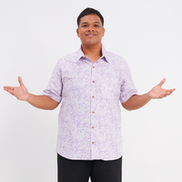 a male model posing in front of a white background while wearing a batik shirt in the pattern lilac pattern