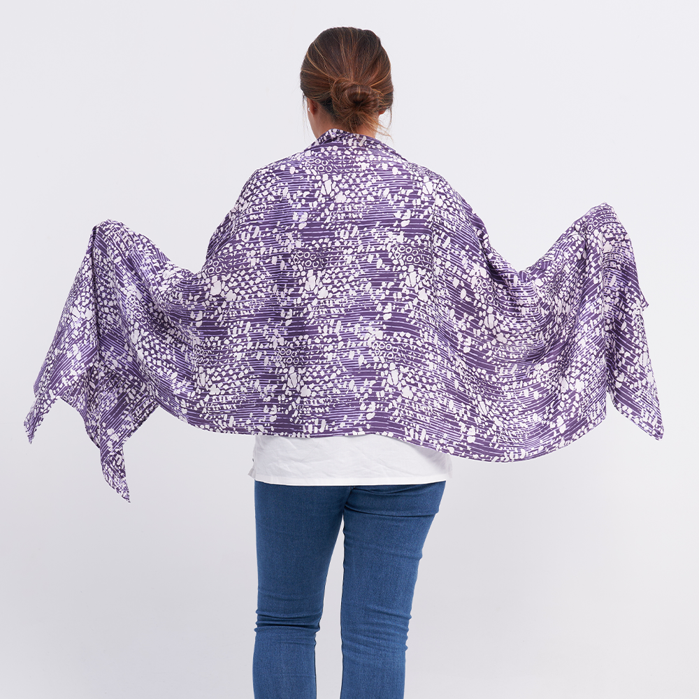 a woman showcasing the batik scarf in the pattern purple bintik against a white background