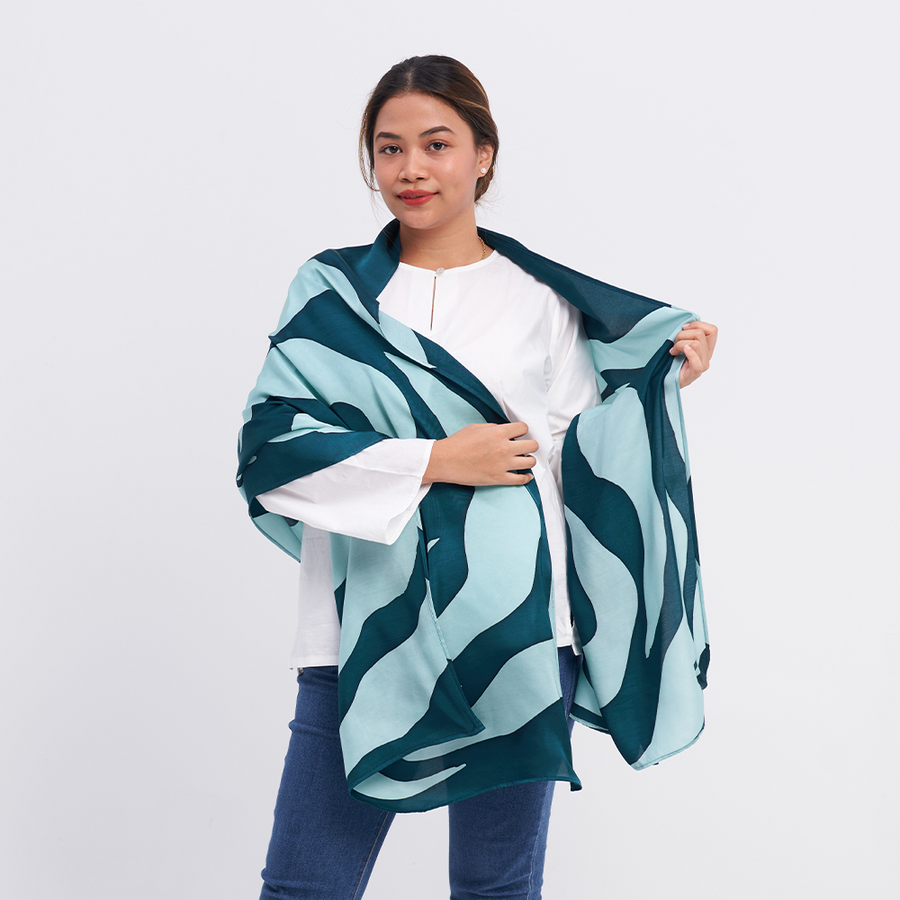 a female model posing with a batik scarf in the pattern teal rose against a neutral background