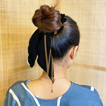 a woman wearing batik scrunchies against a rattan backdrop in the pattern black ecru