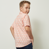 A boy striking a pose while glancing over his shoulder, showcasing the Peach Firework patterned batik shirt