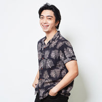 A man standing in front of white background in batik cuban shirt in Black Sawit pattern