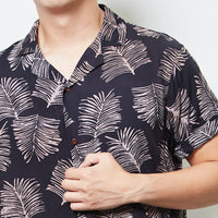 A close up photo of man standing in front of white background in batik cuban shirt in Black Sawit pattern