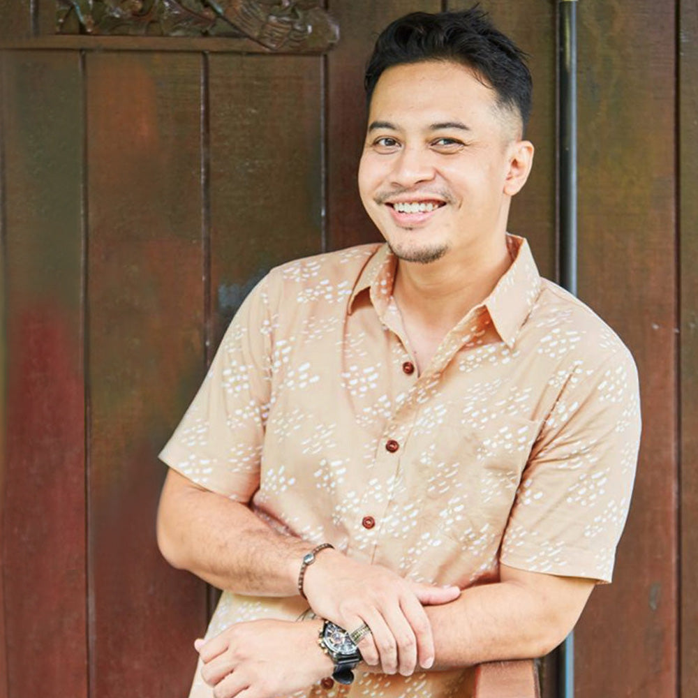 a man leaning at a wooden rail styling batik shirt in latte seed pattern