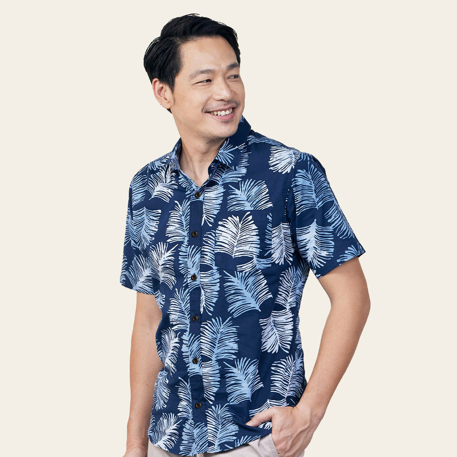 a model posing in front of a neutral background in a batik shirt in the pattern navy sawit