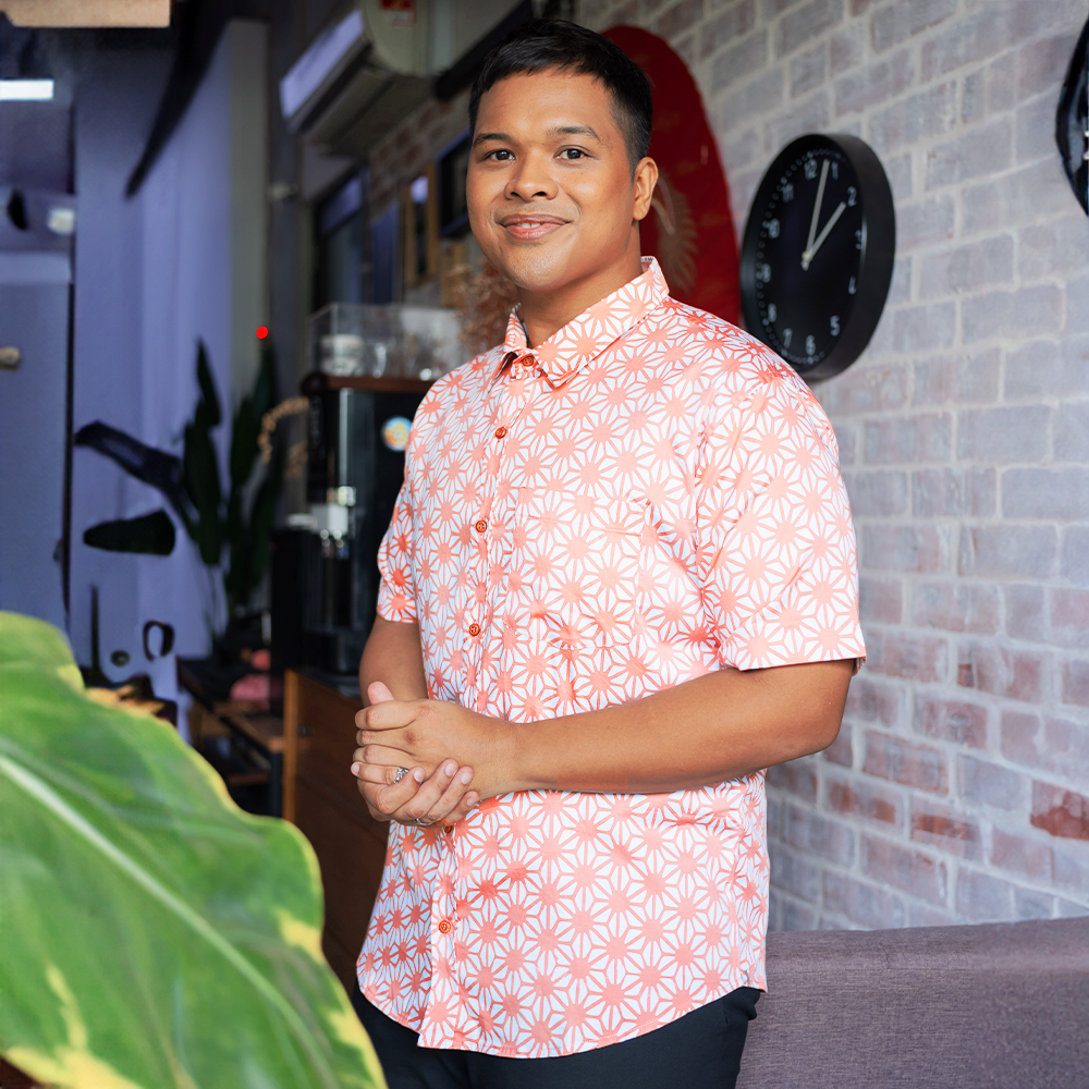a man posing in a lifestyle photo in an authentic batik shirt in the pattern peach firework
