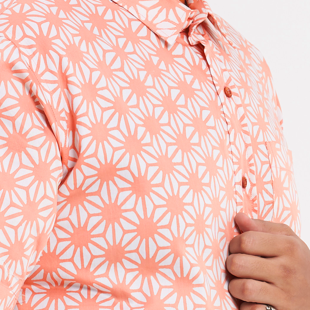 a closeup shot of a male model wearing an authentic batik shirt in the pattern peach firework against a white background
