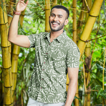 Man with bamboo trees in Malaysia wearing batik men short sleeved shirt in Olive Diwanie.