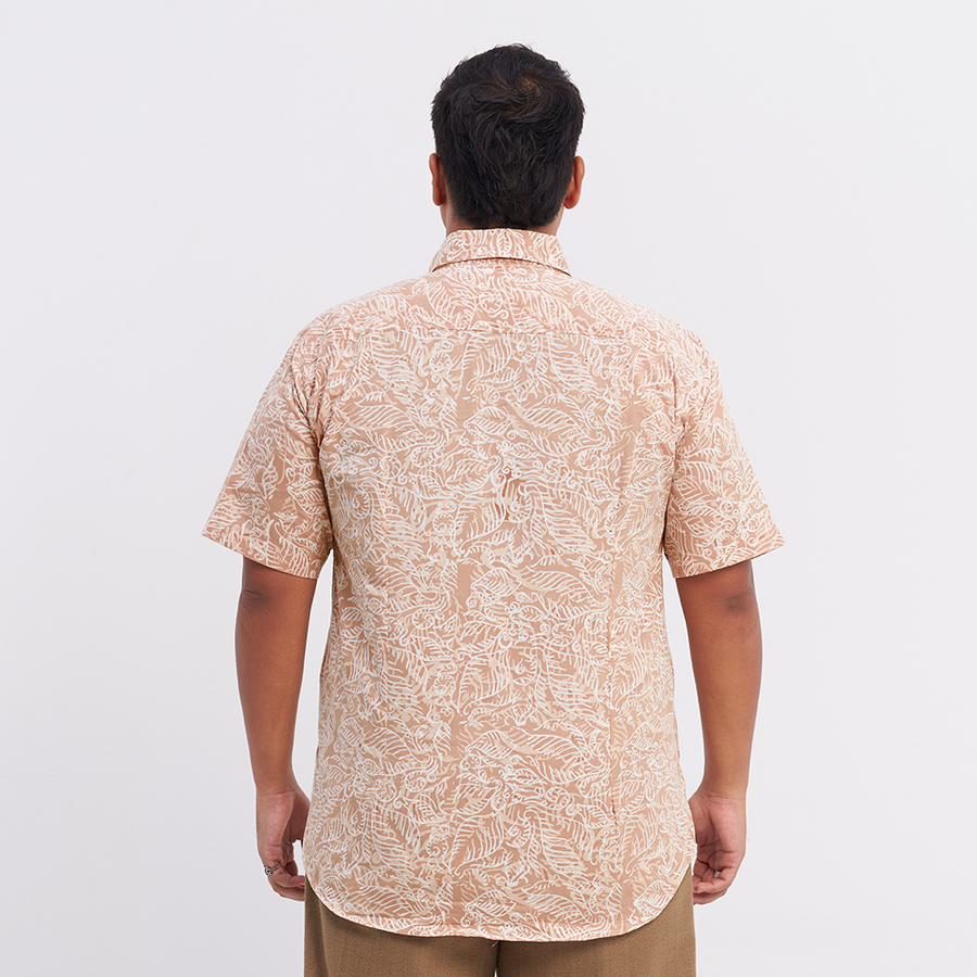 A man standing in front of white background wearing neutral batik shirt color in Tan Nautical fern pattern facing back